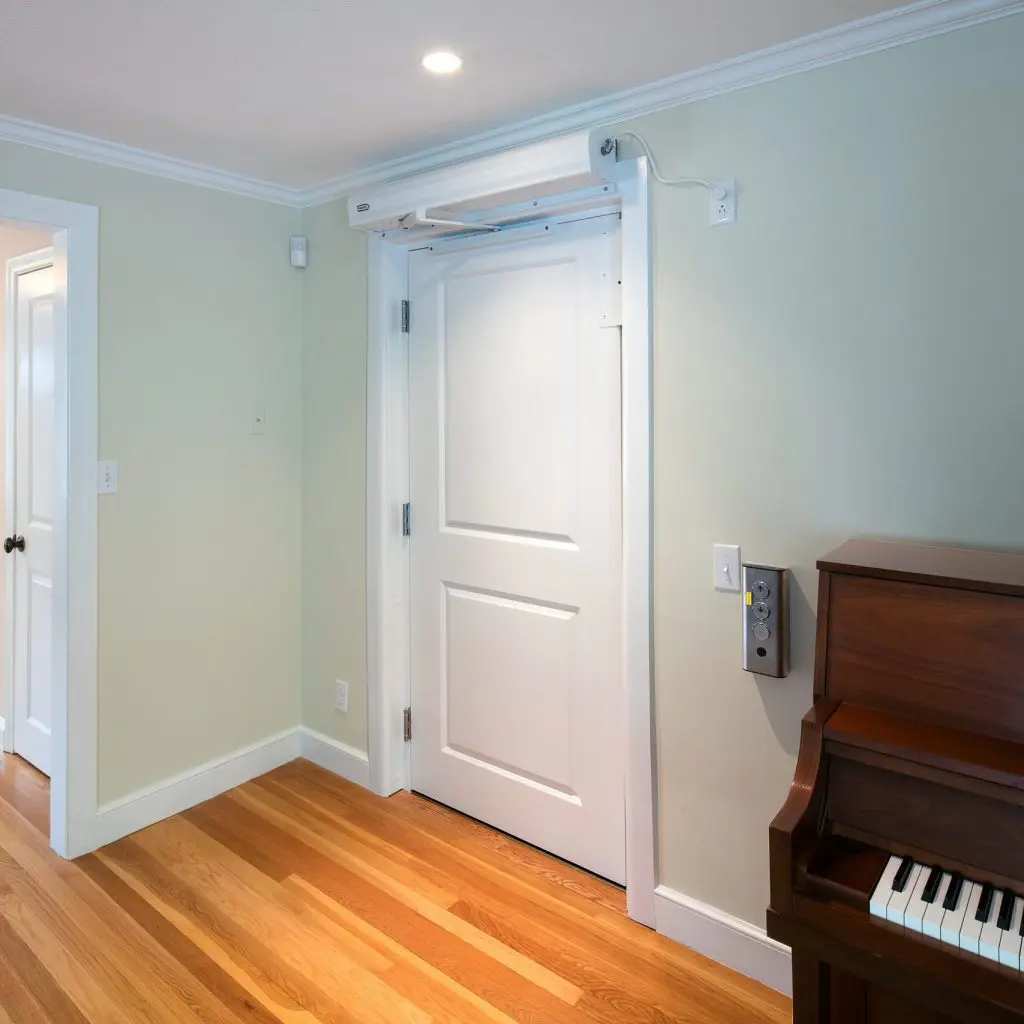interior view of a door, next to a piano, a stair lift chair is seen in the background