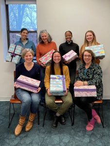 Seven women with decorate shoeboxes in their lapts.