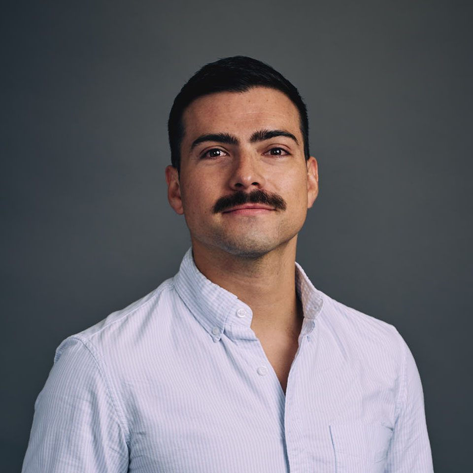 Dark haired man with a mustache in a white shirt